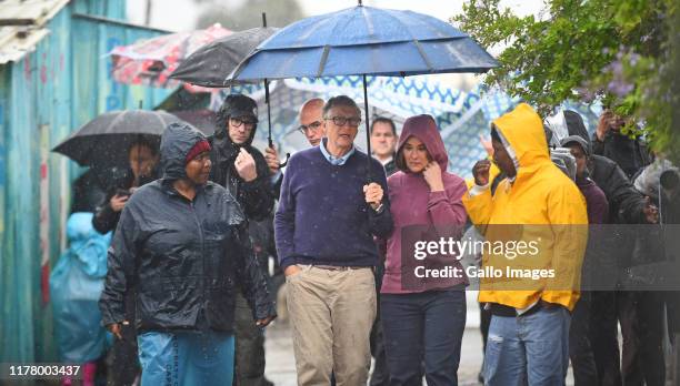 Bill and Melinda Gates brace the rain as they visit the township of Khayelitsha on October 25, 2019 in Cape Town, South Africa. The world?s richest...