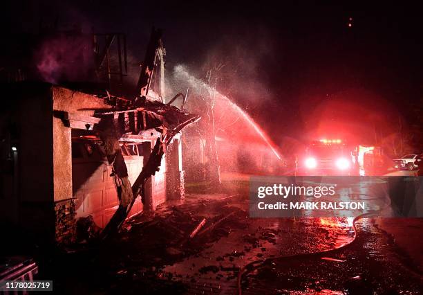 Firefighters hose down a burning house during the Tick Fire in Agua Dulce near Santa Clarita, California on October 25, 2019. - California...