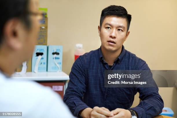 mann zum arzt zur routineuntersuchung in klinik - taiwanesischer abstammung stock-fotos und bilder