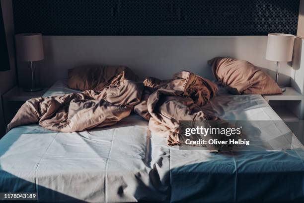 front view of an untidy bed with crumpled bed sheet and two messy pillows in a hotel room - sleeping rough stock pictures, royalty-free photos & images