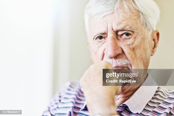 homme aîné regardant inquiété, menton sur la main - vieux grincheux photos et images de collection