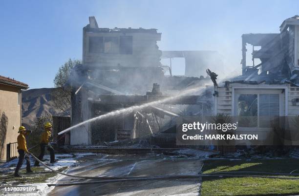 Firefighters hose down a burning house during the Tick Fire in Agua Dulce near Santa Clarita, California, on October 25, 2019. - California...