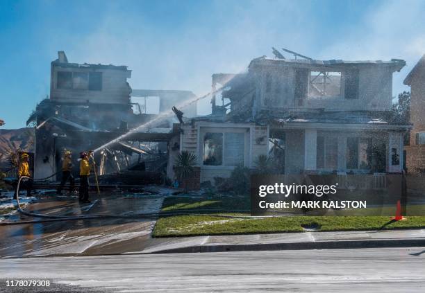 Firefighters hose down a burning house during the Tick Fire in Agua Dulce near Santa Clarita, California on October 25, 2019. - California...