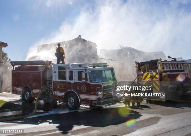 Firefighters hose down a burning house during the Tick Fire in Agua Dulce near Santa Clarita, California on October 25, 2019. - California...