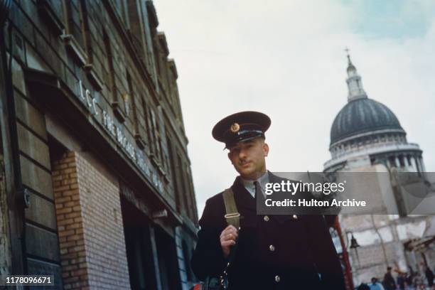 Member of the London Fire Brigade outside the LCC Fire Brigade Station in Cannon Street, with St Paul's Cathedral in the background, London, circa...