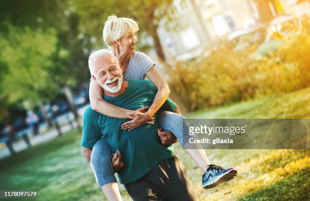 senior couple jogging in a forest. - park couple piggyback stock pictures, royalty-free photos & images