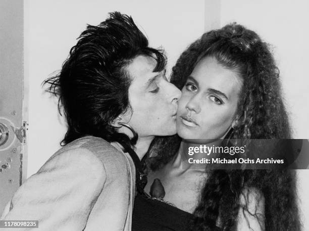 American guitarist and singer Johnny Thunders , who collaborated with hard rock band the New York Dolls, kissing a young woman, circa 1975.