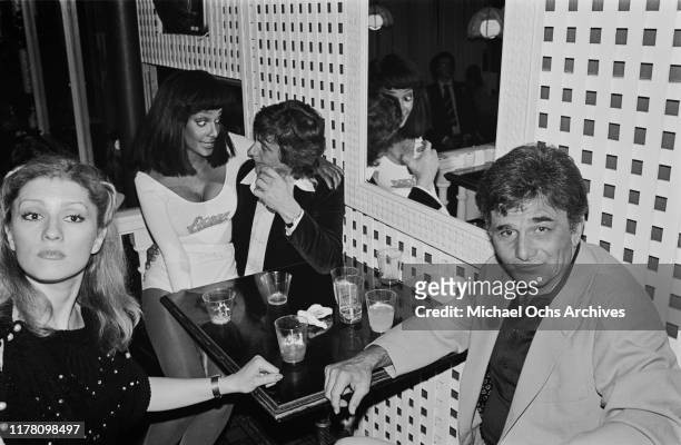 American actor Peter Falk with his wife, actress Shera Danese , and between them, English actor Dudley Moore with a party hostess, at a launch party...