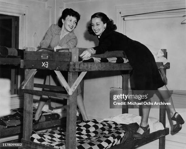 Young actresses Kay Linaker and Mickie Kelly make beds for GIs in the dormitory of the Hollywood Canteen in Los Angeles, California, during World War...