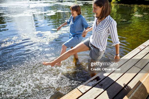 senior woman and her adult daughter wading in a pond - old lady feet 個照片及圖片檔