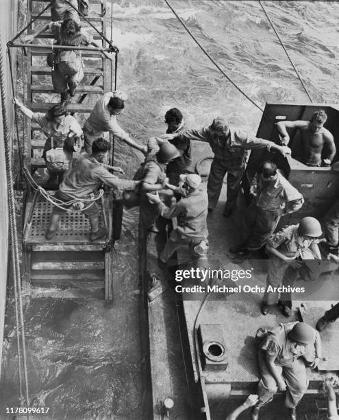 Army nurses are helped onto the landing barge from their troopship at Okinawa, Japan, circa 1960.