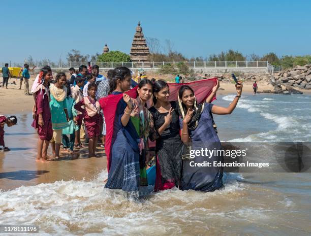 Teenage girls take selfie on the beach in front of Shore Temple, Mahabalipuram, Mamallapuram, India.