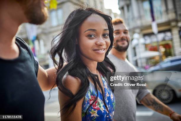 portrait of smiling friends in the city on the go - drei erwachsene stock-fotos und bilder