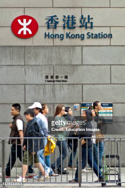 Passersby at the metro station Hong Kong Station, logo of the Hong Kong MTR metro system, Hong Kong.
