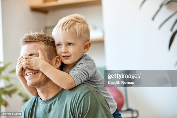 garçon blond mignon de sourire couvrant des yeux du père - scandinavie photos et images de collection