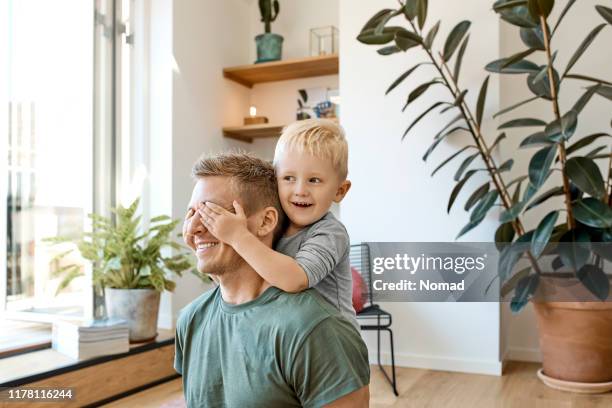 smiling preschool boy covering eyes of father - scandinavia stock pictures, royalty-free photos & images