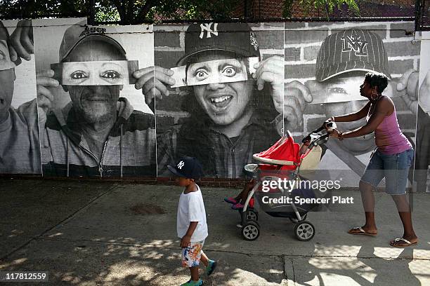 Pictures composed by the French street artist JR are plastered to a wall as part of a community project called "Through A Mother's Eyes," which...