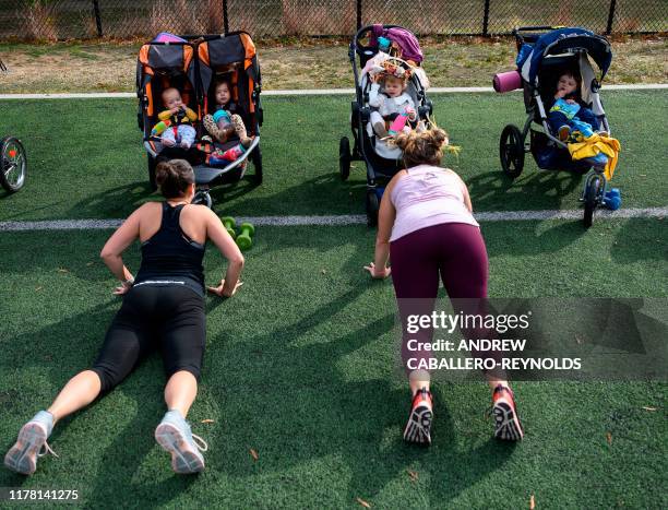 Chidren watch as their moms do pushups during a Halloween themed boot camp style workout, Stroller Strong Moms, geared towards moms in Arlington,...
