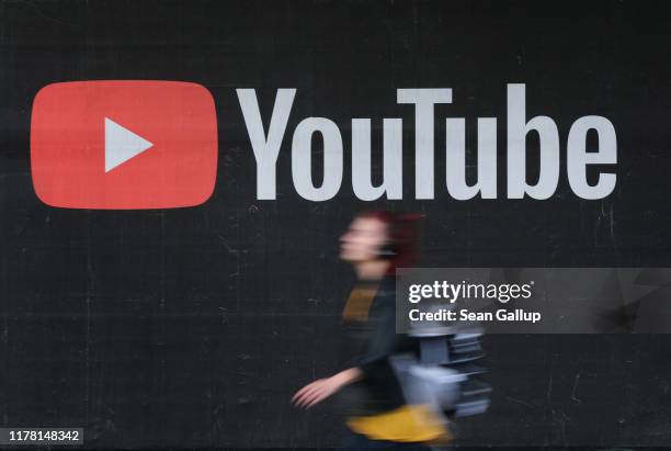 Young woman wearing headphones walks past a billboard advertisement for YouTube on September 27, 2019 in Berlin, Germany. YouTube has evolved as the...
