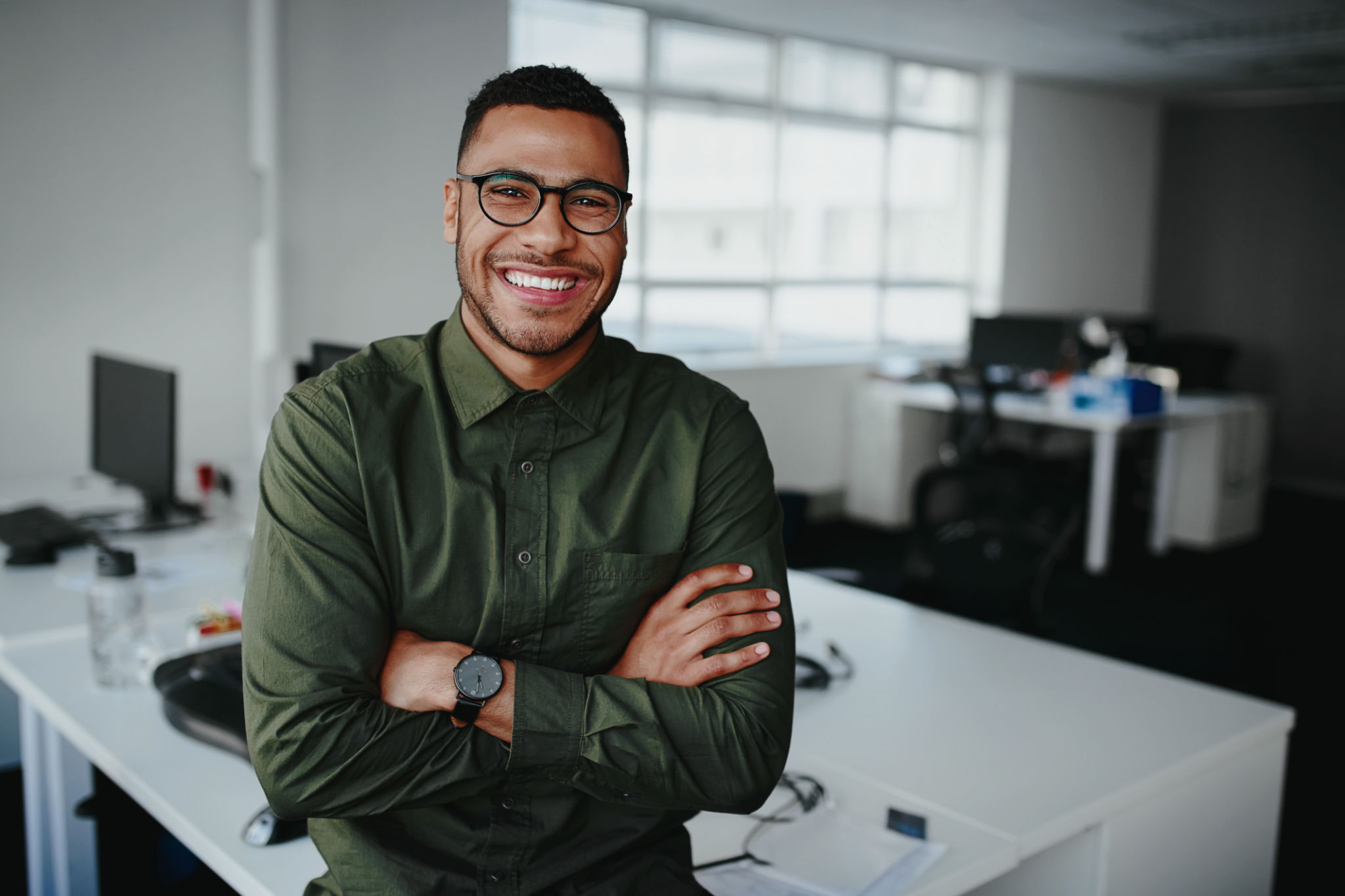 Portrait of a happy confident young african american businessman standing with his arms crossed looking at camera Portrait of a happy confident young african american businessman standing with his arms crossed looking at camera
