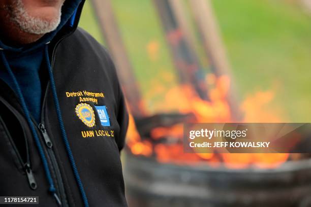 United Auto Workers members stand around a barrel as they stay warm while striking outside of the General Motors Detroit-Hamtramck Assembly plant in...