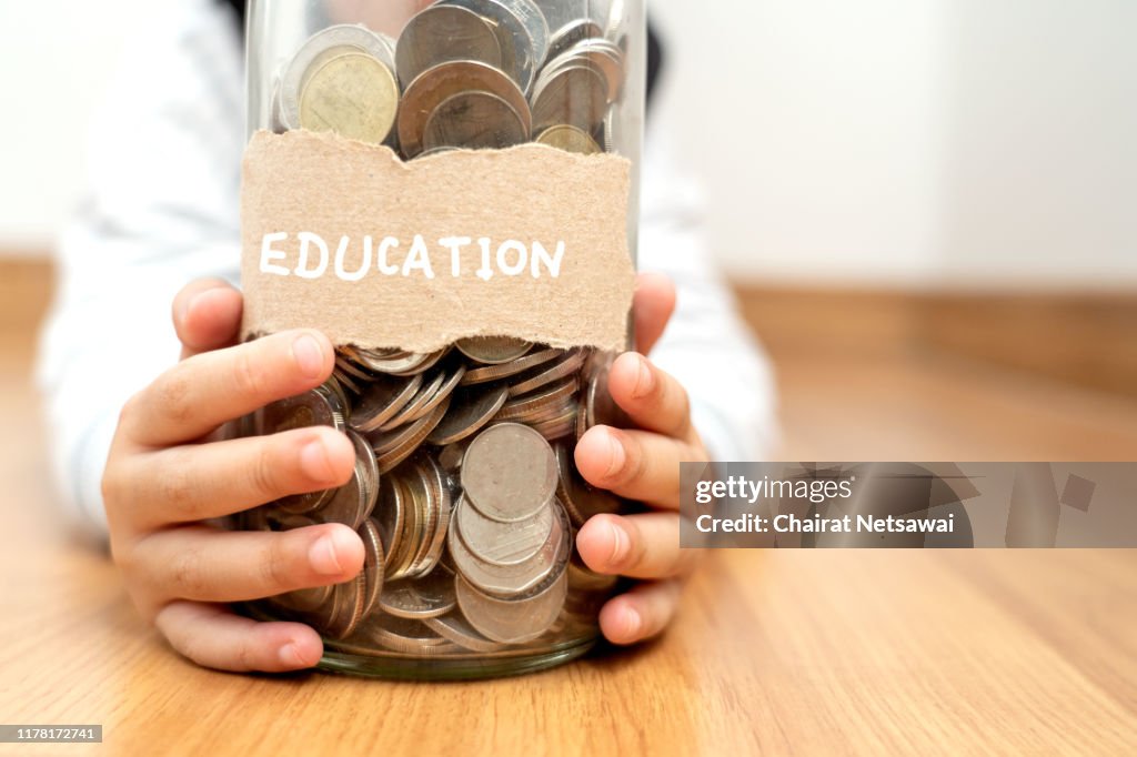 Money in children's hands.happy asian boy holding glass bottle and saving money into glass bottle.Education and concept.