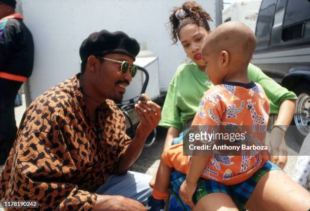 View of American film director John Singleton, in sunglasses and a beret, as he speaks with a young boy on the set of his movie 'Poetic Justice,' Los...
