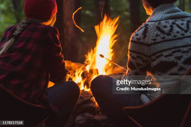 a couple roast marshmallows together - fogueira de acampamento imagens e fotografias de stock