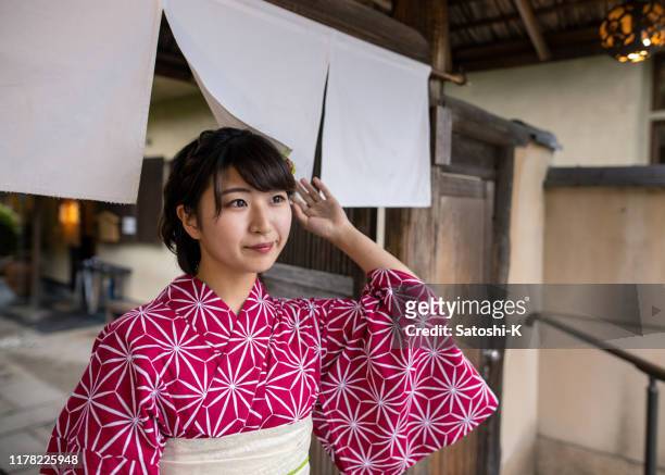 beautiful woman in yukata walking through noren gate - noren stock pictures, royalty-free photos & images