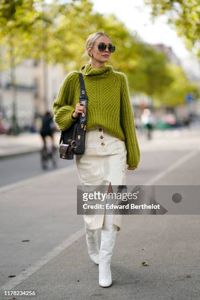 Leonie Hanne wears sunglasses, a green wool turtleneck knitted pullover, a Givenchy bag, white side slit skirt, white boots, outside Beautiful...