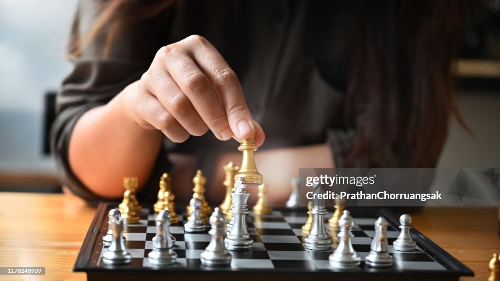Cropped shot young woman paling chess board on table.