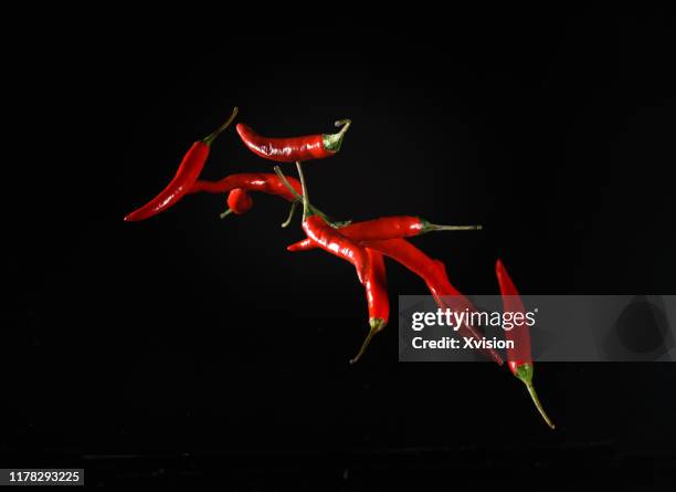 red chili flying in mid air captured with high speed sync. - pimenta de caiena condimento - fotografias e filmes do acervo