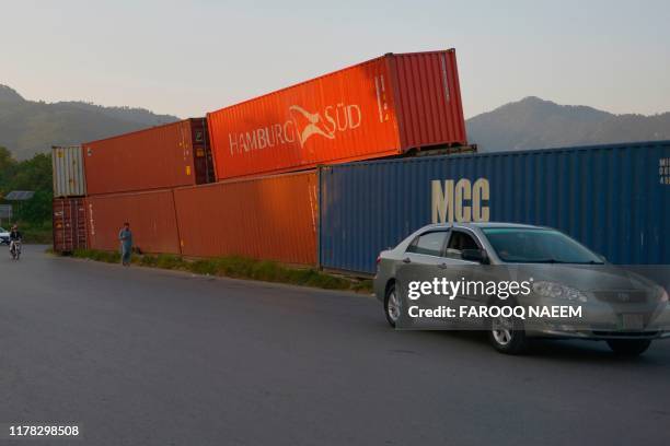 Commuters ride past containers placed on roadside in Islamabad on October 26 ahead of opposition party Jamiat Ulema-e-Islam anti-government protest....