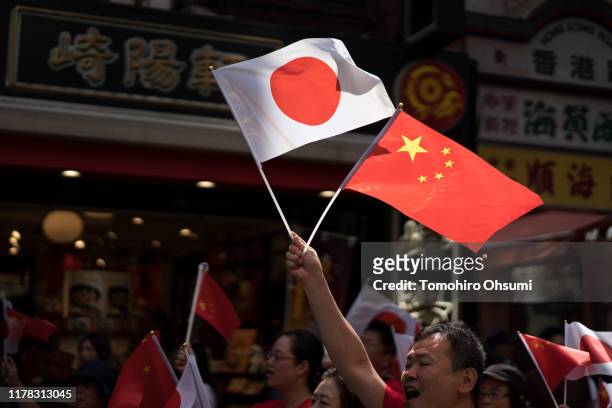 Man holds Chinese and Japanese national flags during a parade celebrating the 70th anniversary of the founding of People's Republic of China at...