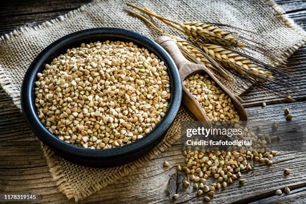 dietary fiber: wholegrain buckwheat in a black bowl on rustic wooden table - buckwheat stock pictures, royalty-free photos & images