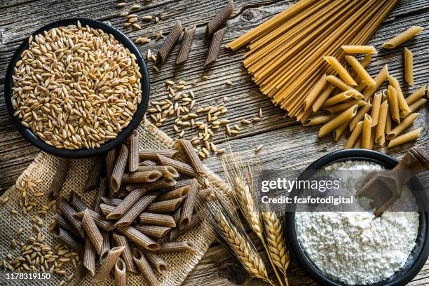 dietary fiber: wholegrain pasta, spelt and flour on rustic wooden table - wholegrain stock pictures, royalty-free photos & images