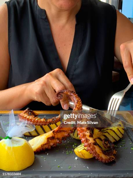 woman in restaurant and eating octopus with eating utensil - tentacle imagens e fotografias de stock