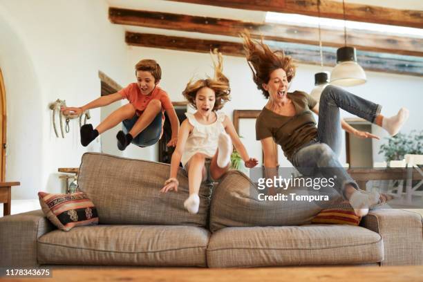rennen um den besten platz auf dem sofa. mutter und kinder springen. - sofa stock-fotos und bilder