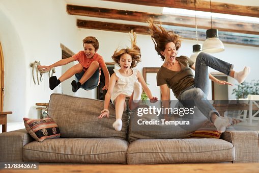Race for the best spot on the sofa. Mother and children jumping. Race for the best spot on the sofa. Mother and children jumping.