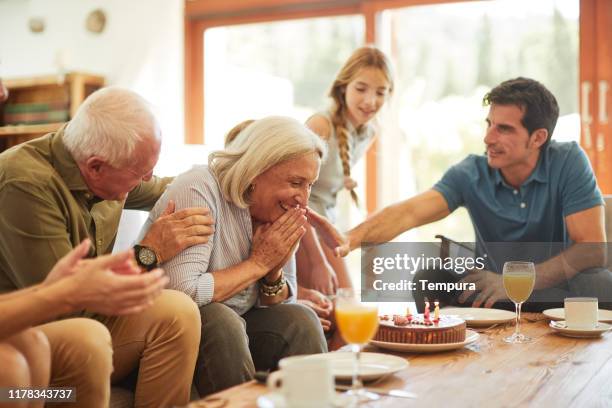 grandmother gets a surprise birthday cake on a family gathering. - surprise birthday party stock pictures, royalty-free photos & images