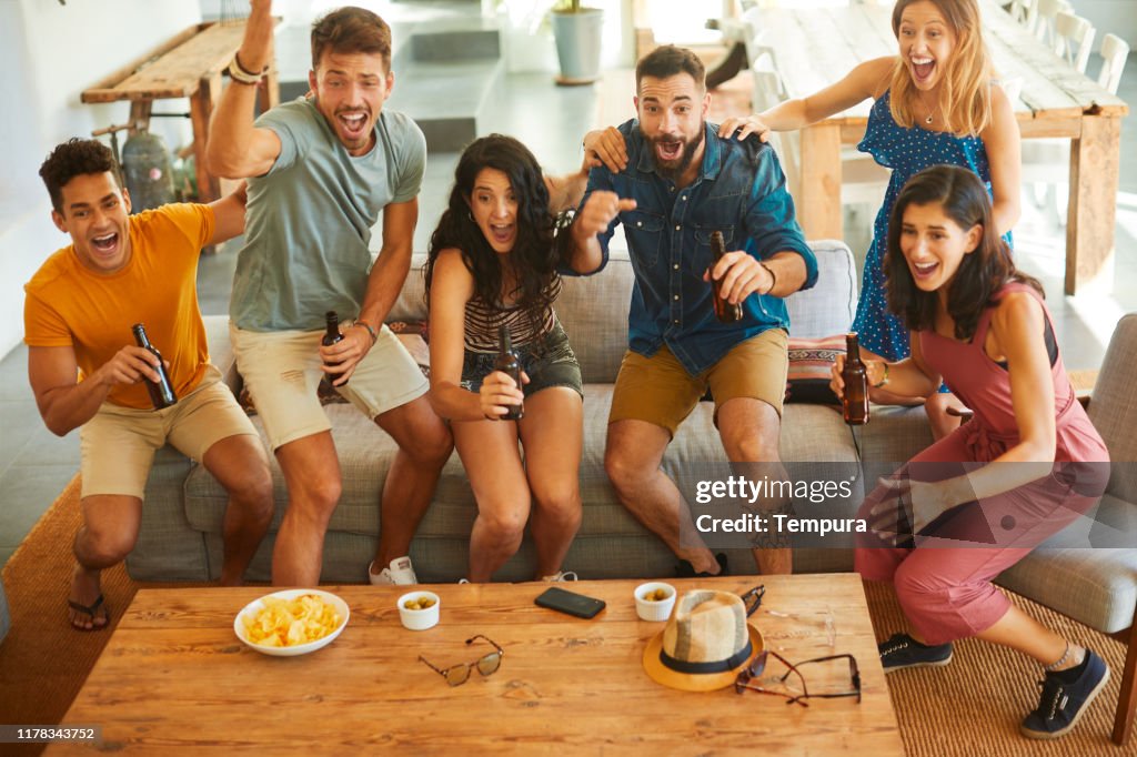 Gruppe von Freunden springen vor Freude, wenn ihr Team ein Tor erzielt.
