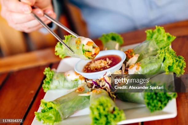 holding fresh spring roll with chopsticks - spring roll stock pictures, royalty-free photos & images