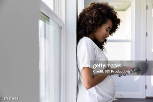 profiel weergave van zwangere vrouw kijken naar ultrasone foto's - ultrasound scan stockfoto's en -beelden