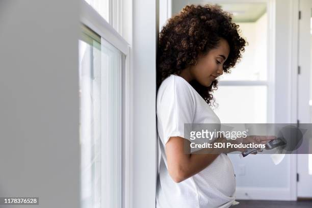 profile view of pregnant woman looking at ultrasound photos - girly pregnant stock pictures, royalty-free photos & images