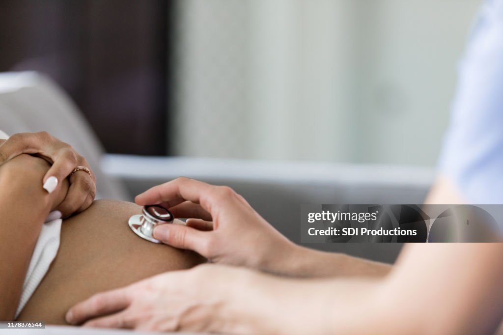 Close up photo of nurse using stethoscope for prenatal check