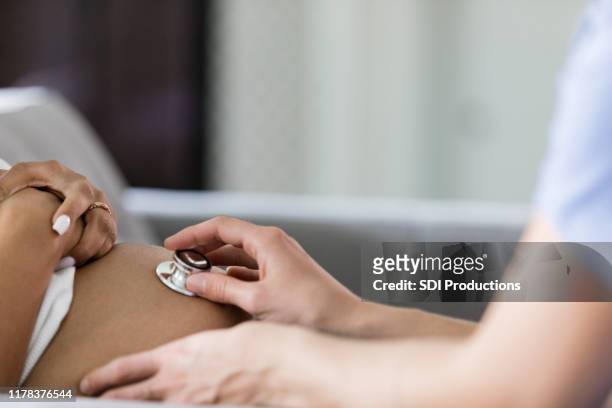 close up photo of nurse using stethoscope for prenatal check - prenatal care stock pictures, royalty-free photos & images