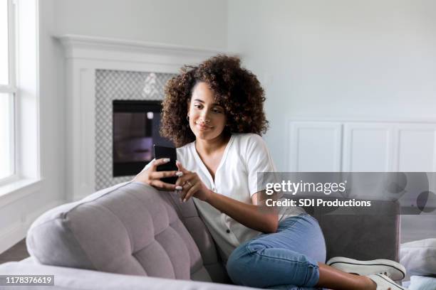 woman uses smartphone in new home - millennial home ownership stock pictures, royalty-free photos & images