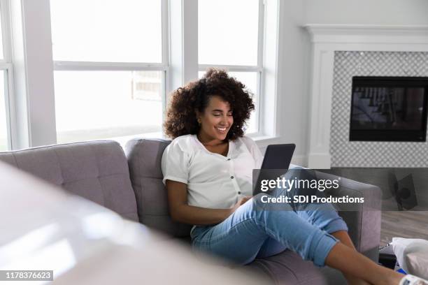 pregnant woman uses digital tablet to video chat with friend - ereader stock pictures, royalty-free photos & images