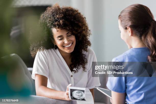 excited pregnant woman looking at sonogram image - instrumento para diagnóstico imagens e fotografias de stock