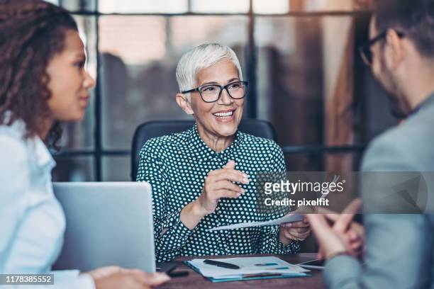 una empresaria sénior hablando con su equipo - altos cargos directivos fotografías e imágenes de stock